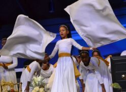 Little girl dancing with flags with other girls dancing behind her