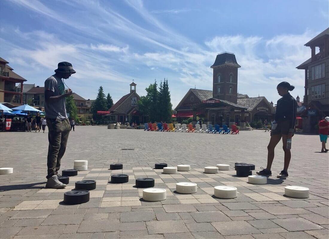 A boy and girl playing a human size checkers or game board outside