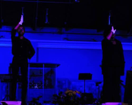 Two ladies wearing white gloves having one hand raised