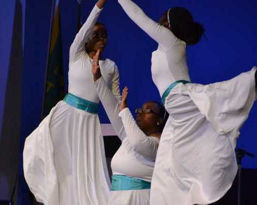 Dancers reaching out hands together to form a triangle