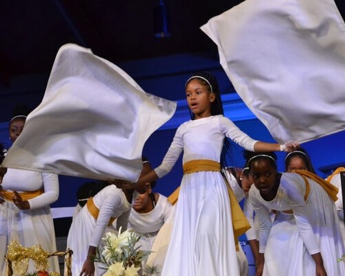 Little girl dancing with flags with other girls dancing behind her