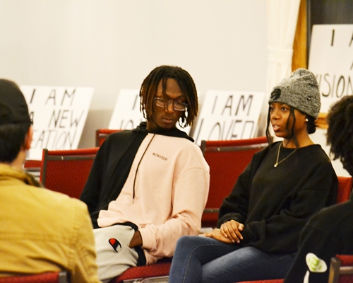 A boy in a group turns his head towards a girl who is talking to the group